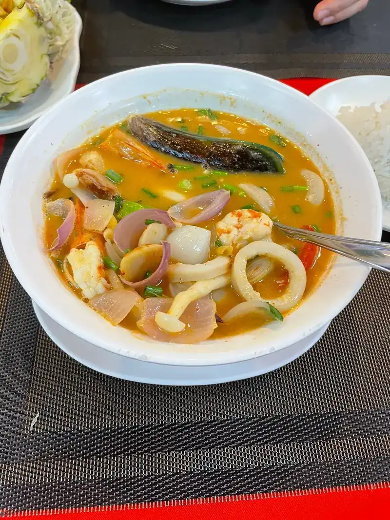 A bowl of seafood tom yum with squid, prawns and mushrooms