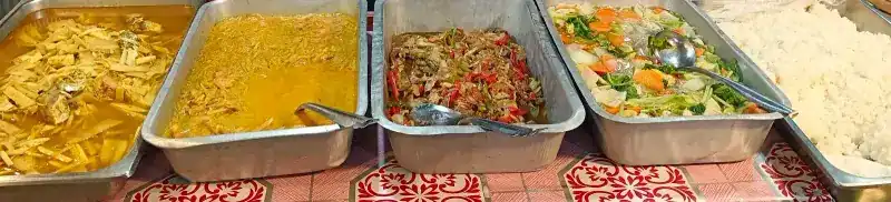 Trays of curries and stir-fries with rice on a patterned tablecloth