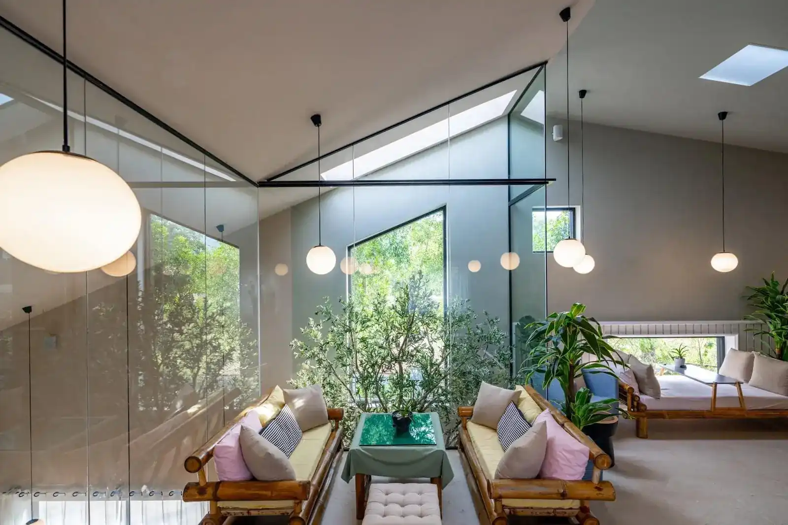 Inside Origami: glass walls, skylights, round pendant lamps and bamboo sofas around a green table