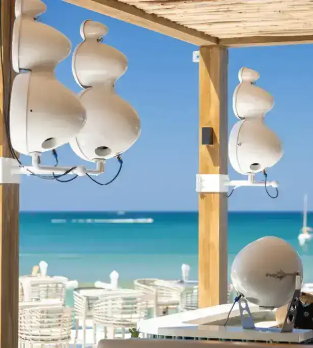 White speakers hung from a teak post at the DJ booth, the sea behind