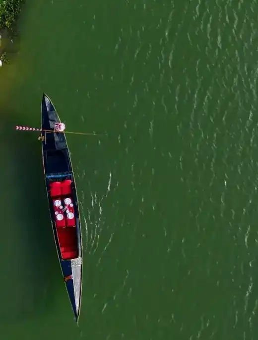 Seen from straight above: a gondola on green water, a table laid in red at its centre