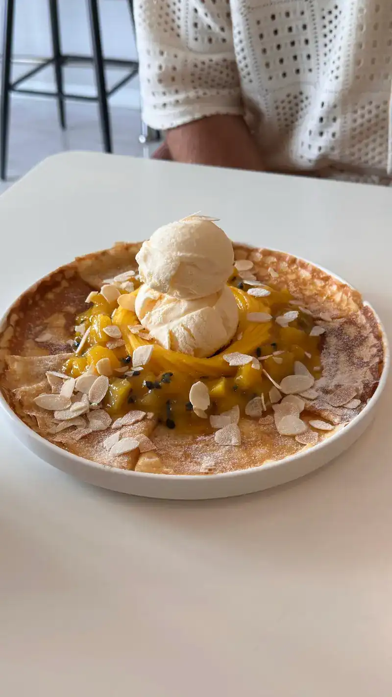 A thin pancake with mango, sliced almonds and scoops of ice cream