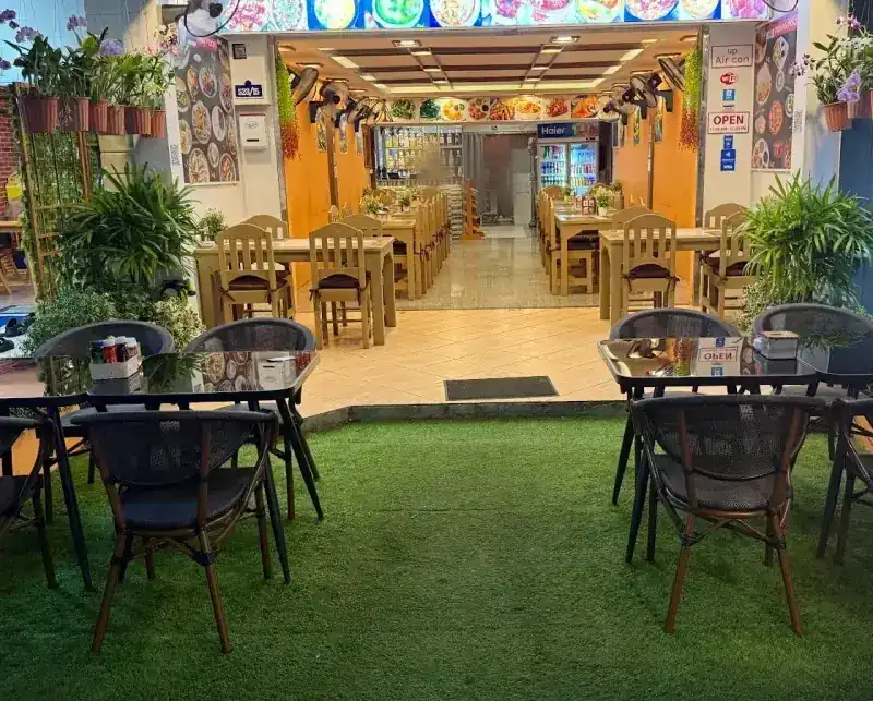 The front of the restaurant: tables on green turf and the dining room behind