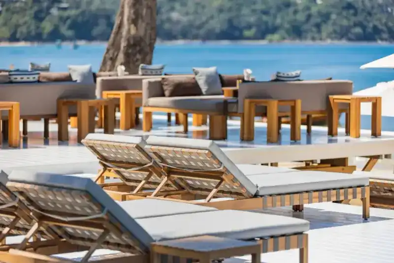 Teak sunbeds and sofas on the deck above the sea