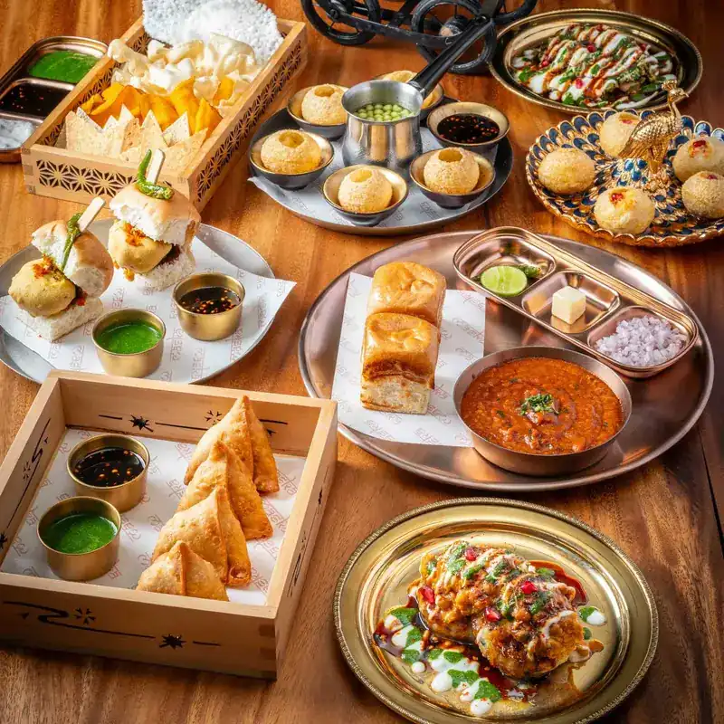 A table of Indian street food: gol gappe, samosas, stuffed buns and chutneys