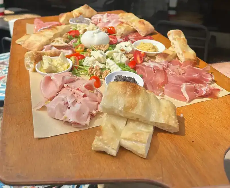 A wooden board of cured meats, cheese and focaccia