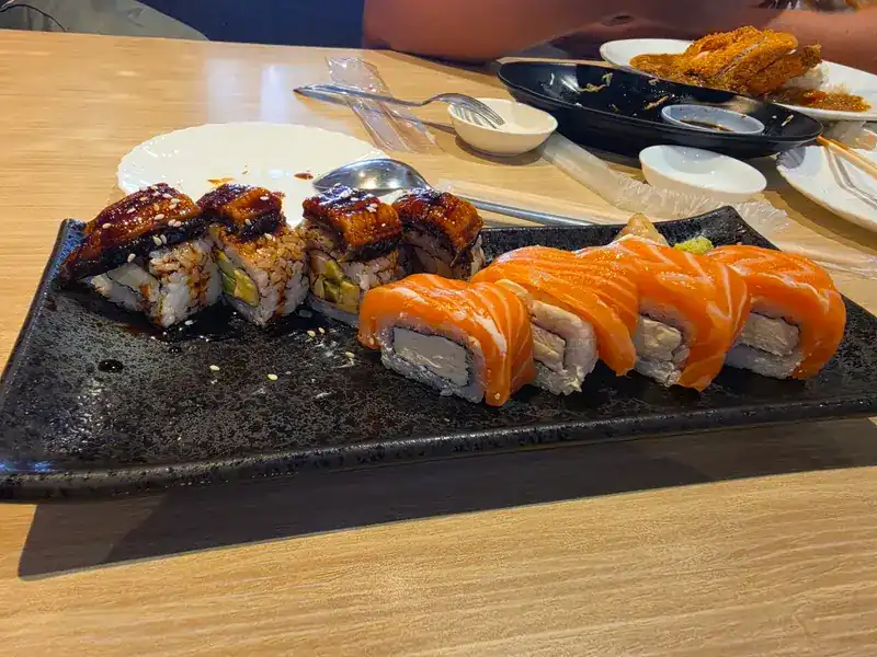 Eel maki and salmon-topped rolls on a dark stone plate