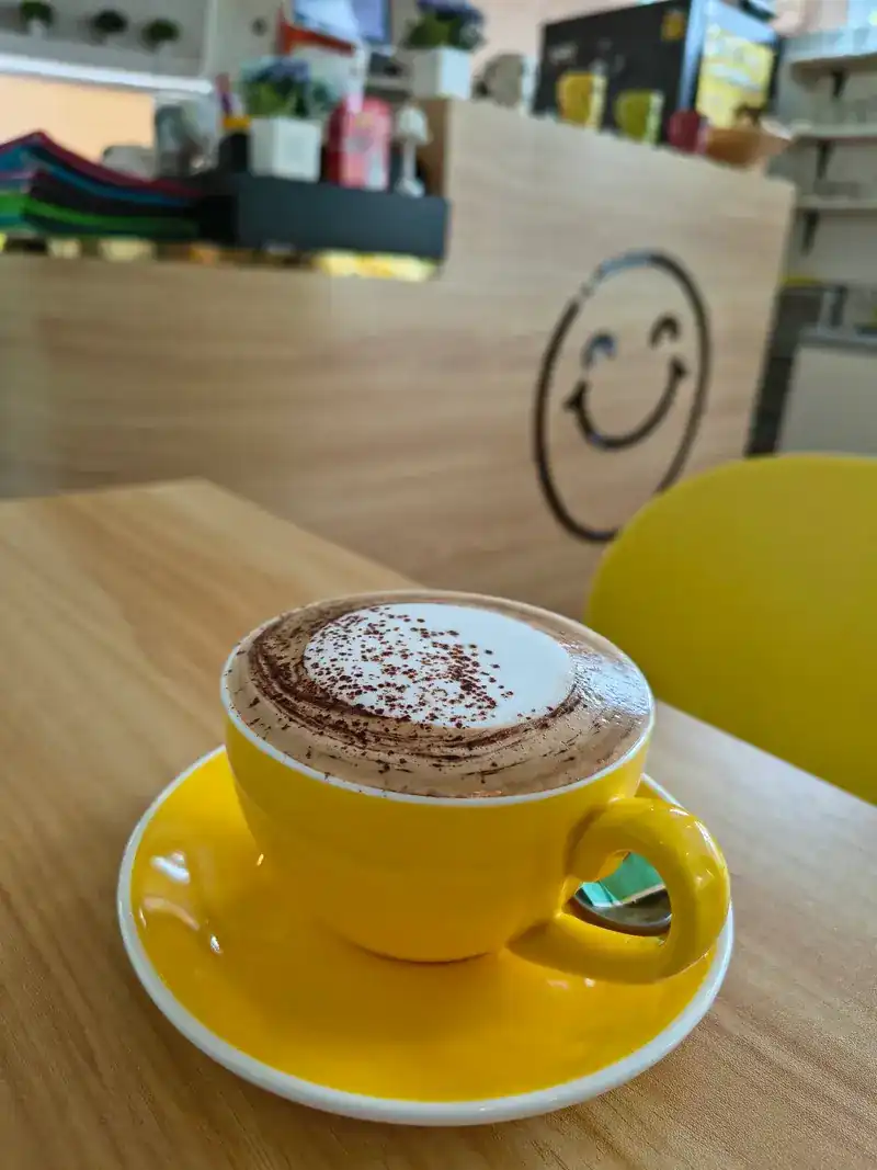 A coffee with cocoa on top in front of the smiley counter