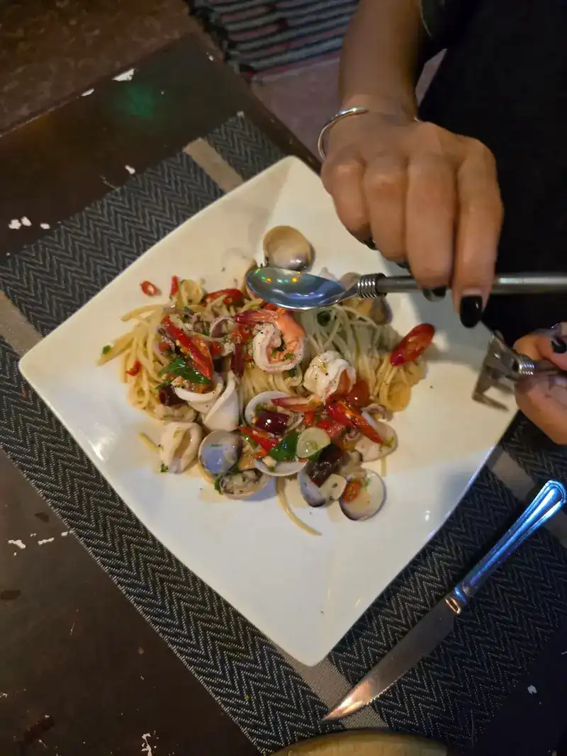 Seafood spaghetti with prawns, clams and fresh chilli on a square white plate