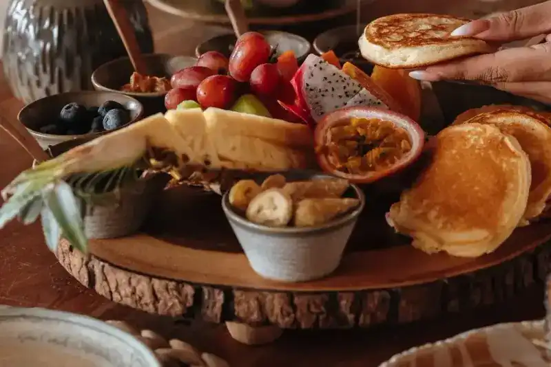 Pancakes, dragon fruit, passion fruit, grapes and pineapple on a wooden board