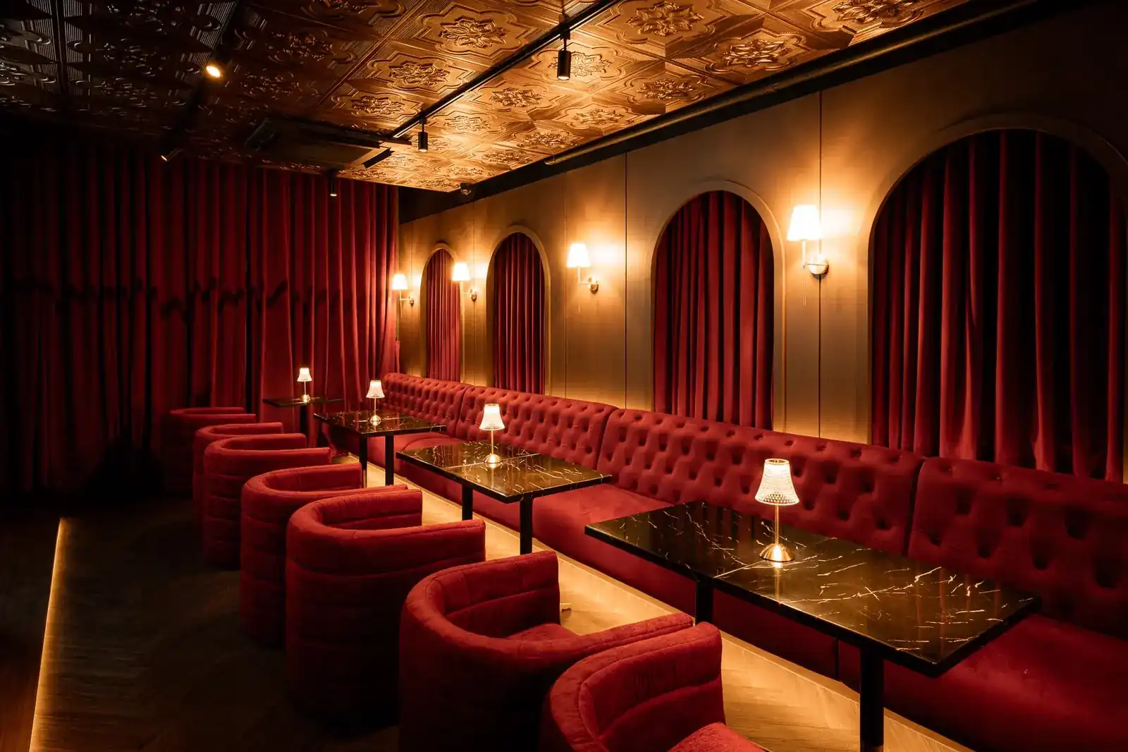 The Moonshine lounge: red velvet booths, curtained arches and small lamps on black marble tables