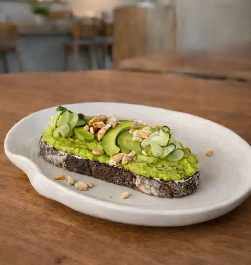 Avocado toast on dark sourdough with cucumber ribbons and cashews