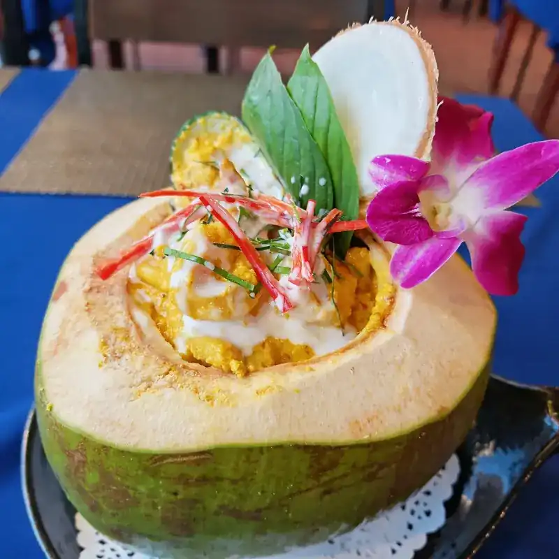 Curry served in a young coconut, topped with an orchid