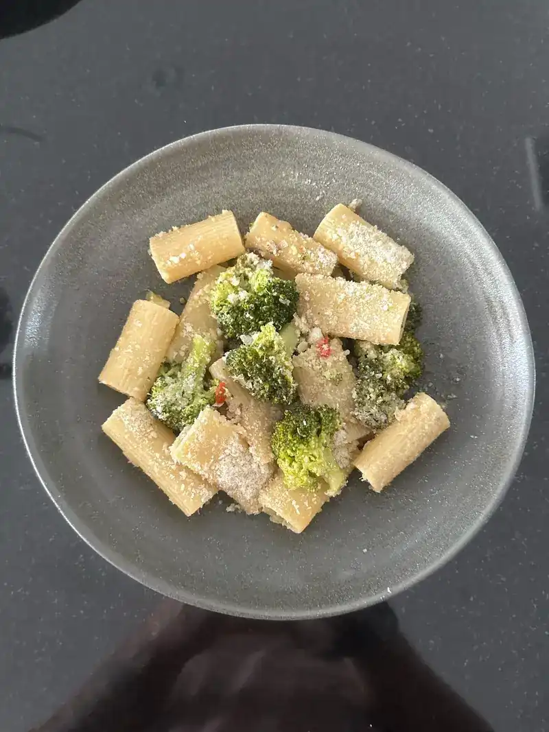 Rigatoni with broccoli and grated cheese in a grey bowl