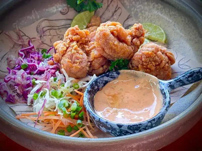 Fried chicken pieces with a pink dipping sauce and shredded cabbage