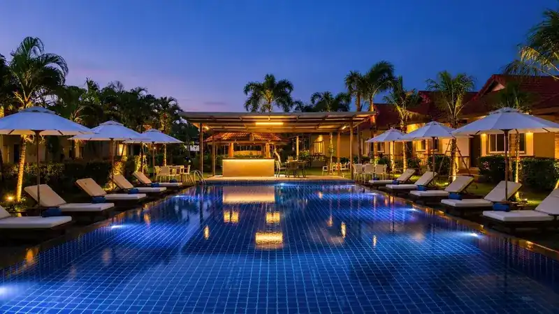 The pool lit up at dusk, umbrellas folded along the edge
