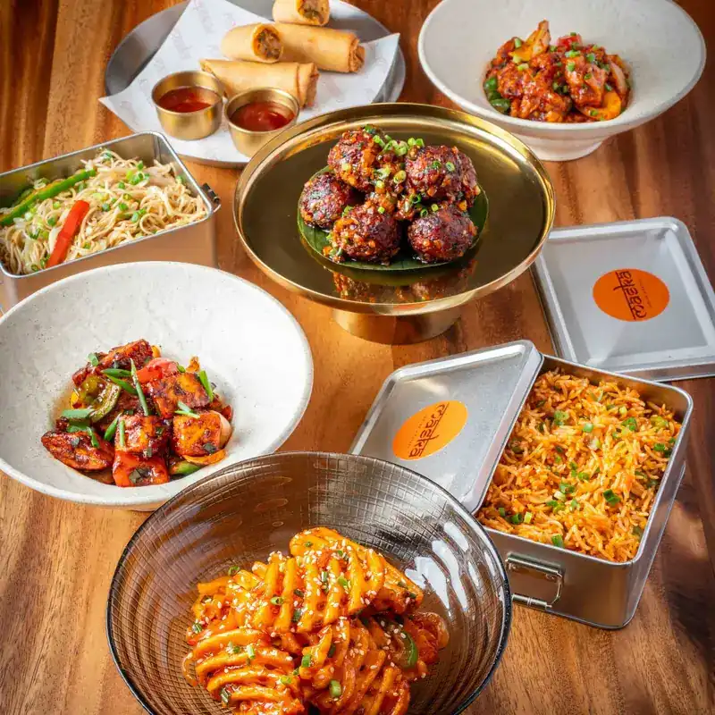 Chilli-glazed dishes, noodles and fried rice in steel tiffin boxes