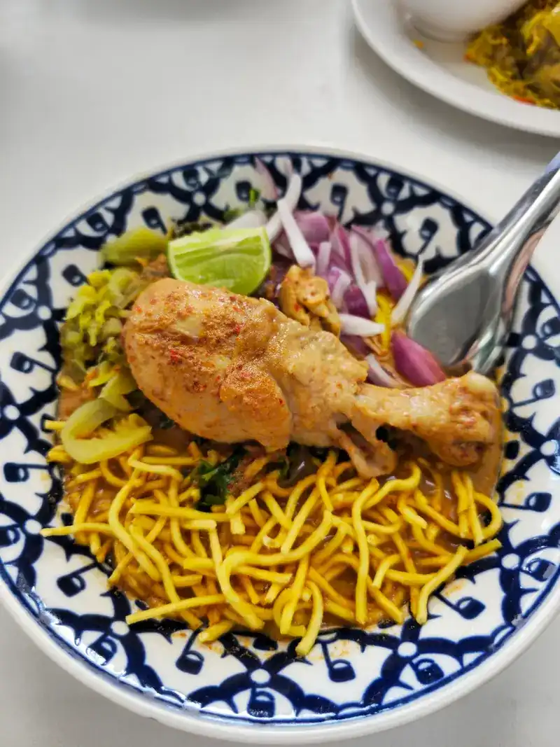 Khao soi with chicken, red shallots, lime and pickled greens