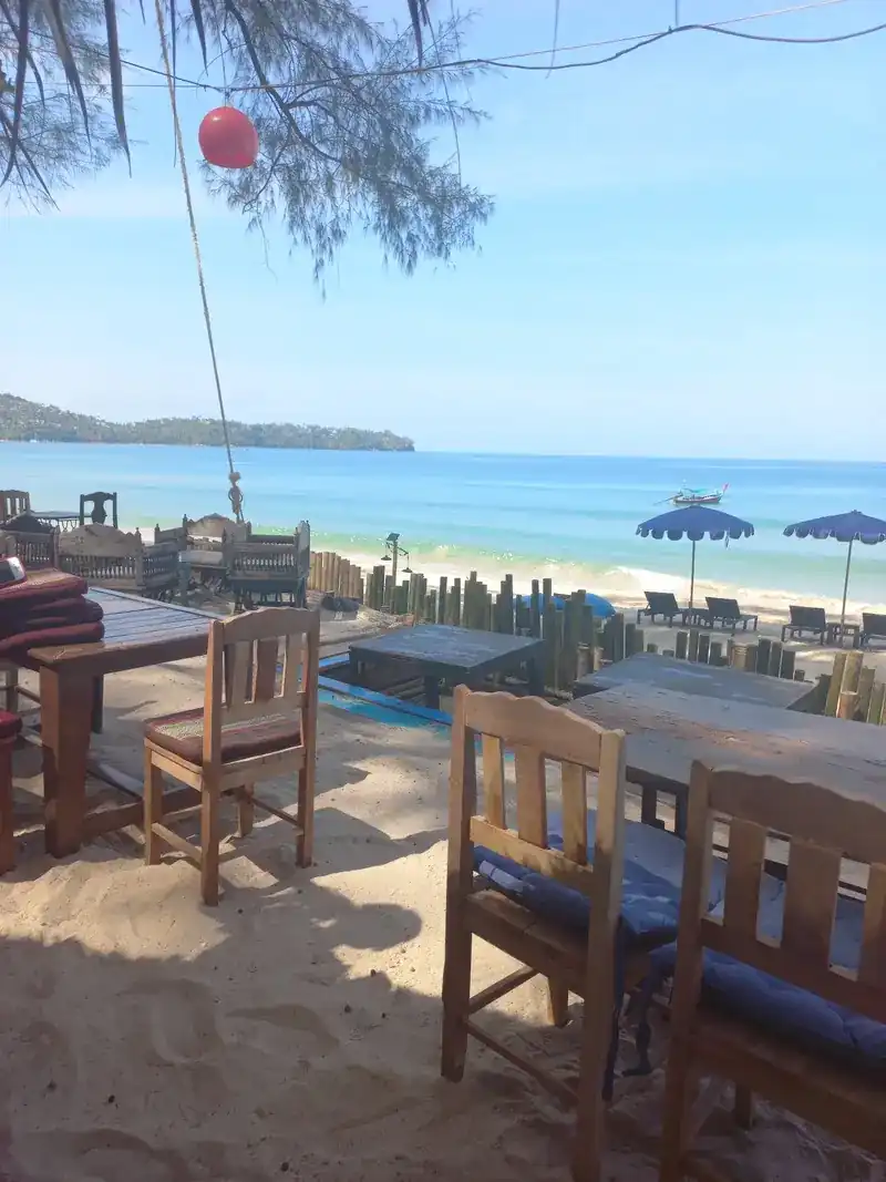 View from the tables across the sand to the sea and blue beach umbrellas / มองจากโต๊ะข้ามผืนทรายไปยังทะเลและร่มชายหาดสีน้ำเงิน