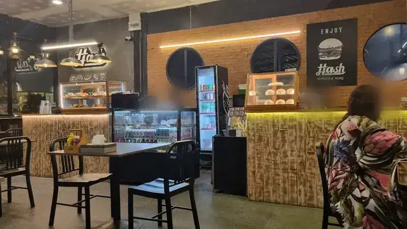 Inside Hash: a brick wall with round windows, a counter with glass display cases and pendant lamps