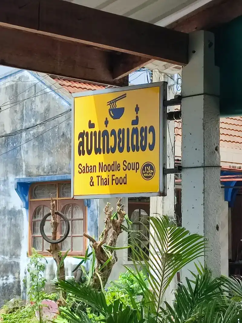 The yellow Saban Noodle Soup & Thai Food sign with the halal mark, hanging at the shop
