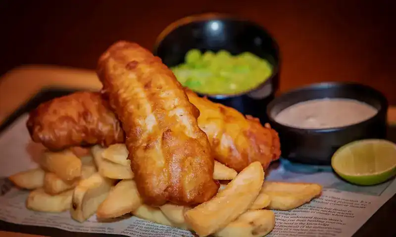 Beer-battered fish with thick-cut chips, mushy peas, tartar sauce and lime