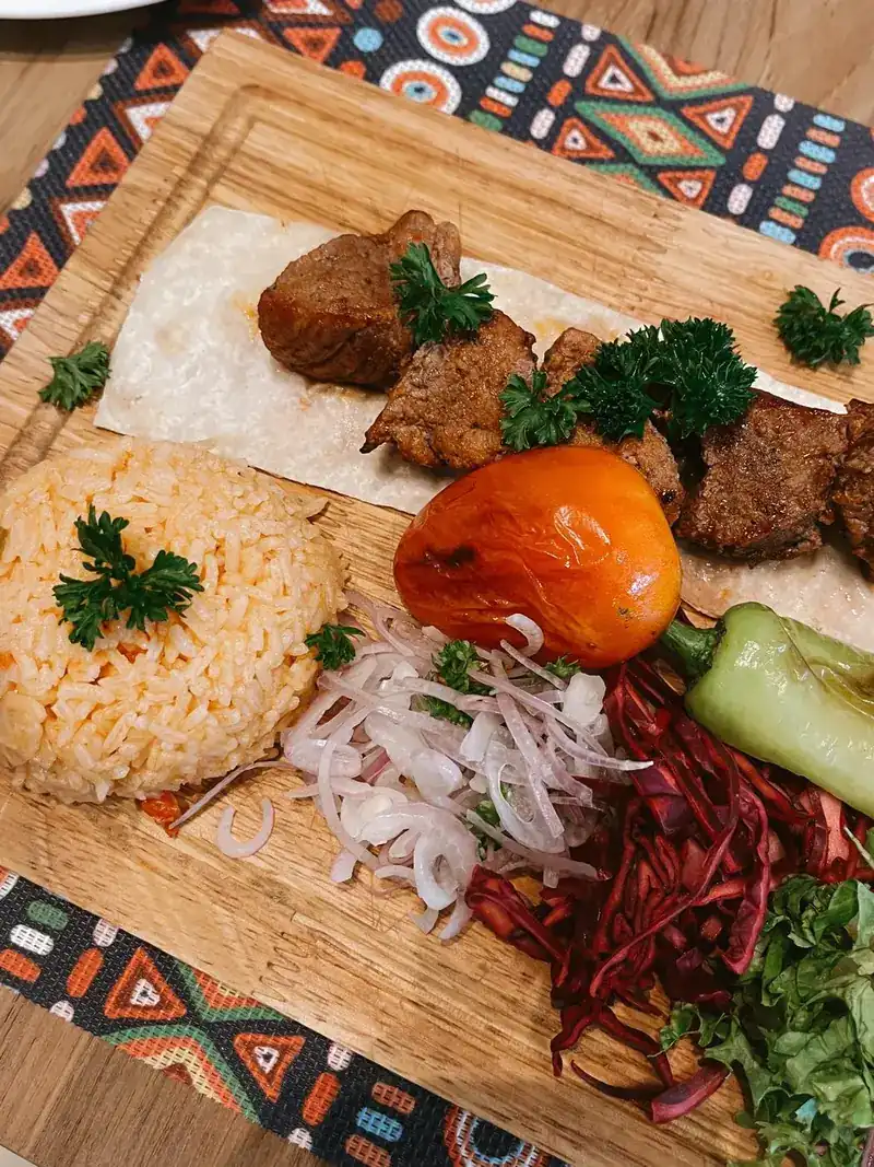 Grilled meat with rice, a grilled tomato, green pepper and onion