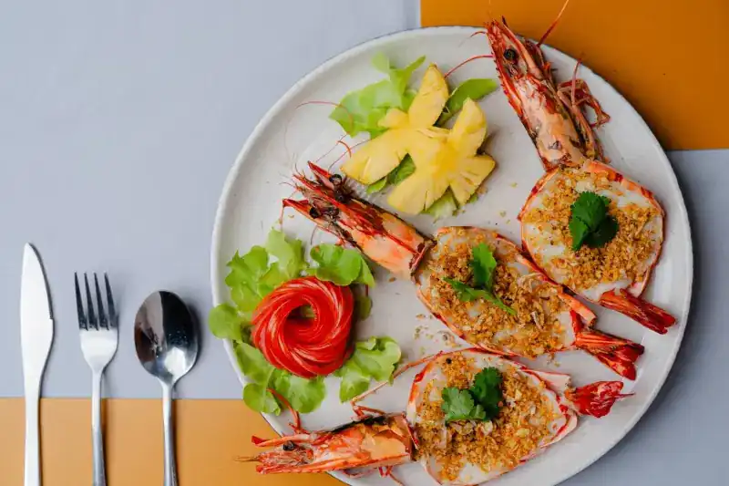 Split prawns topped with fried garlic on a white plate