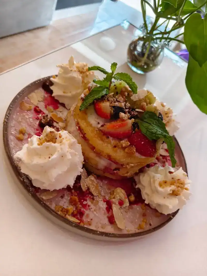 Pancakes with strawberries, whipped cream, mint and crumble