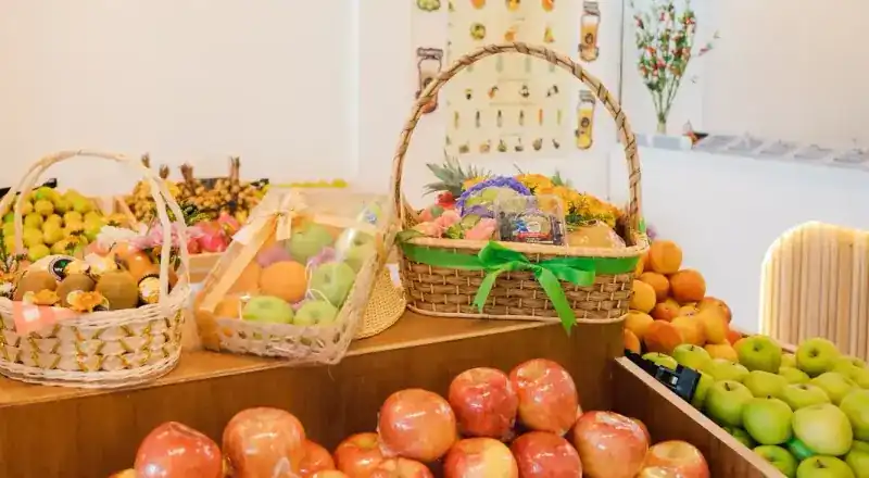 The fruit counter: red and green apples, oranges and baskets of fruit tied with ribbon