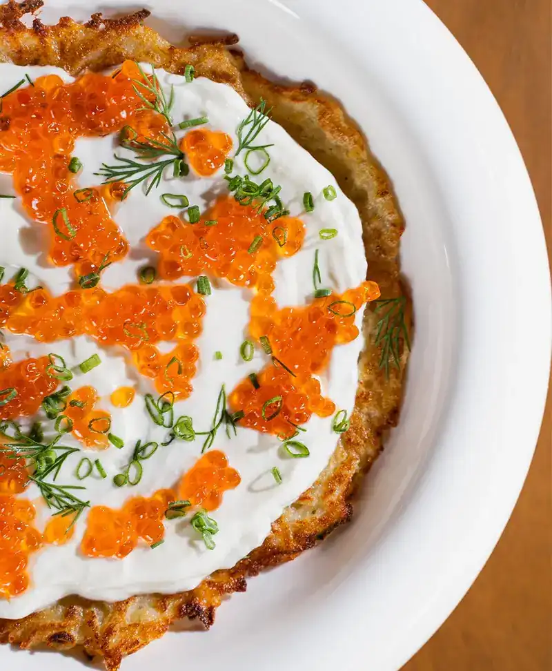 Potato pancake with red caviar, sour cream, dill and chives