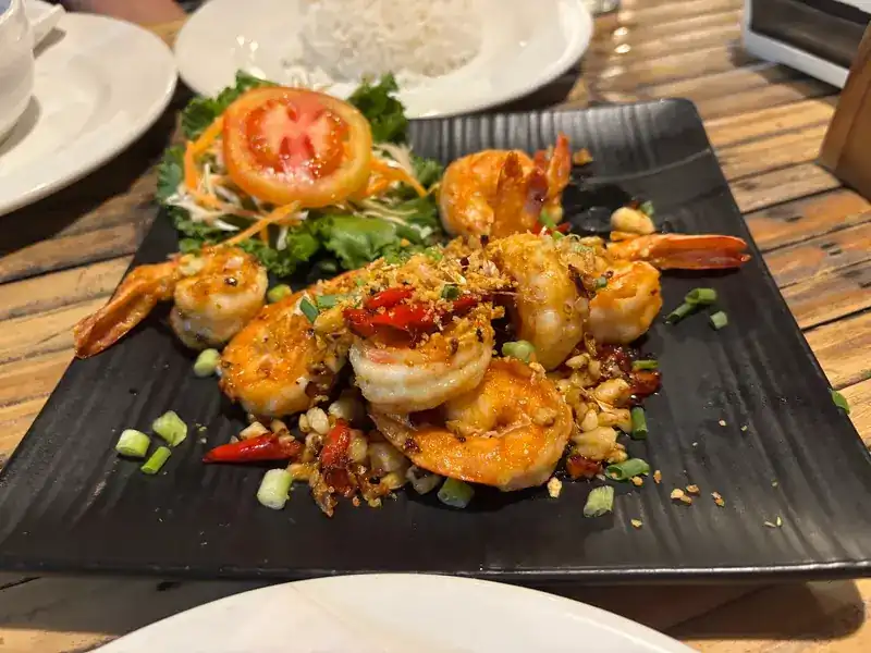 Prawns with fried garlic and chilli on a black plate