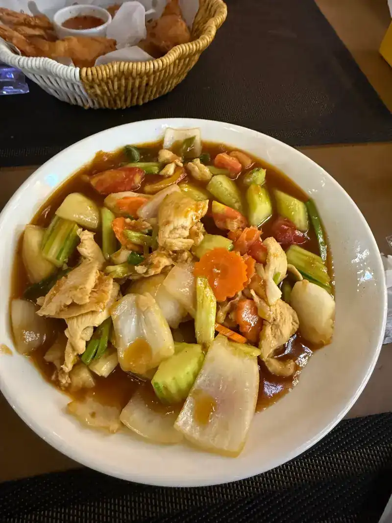 Chicken stir-fried with cucumber, onion, tomato and carrot, with fried snacks in a basket behind