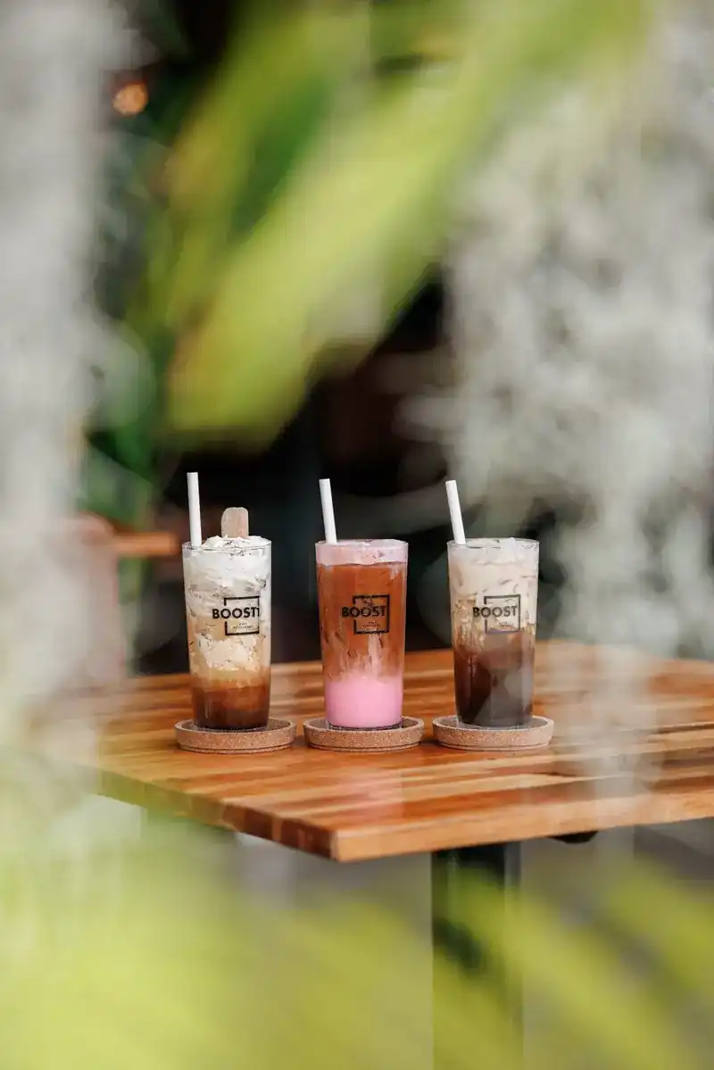 Three iced drinks in BOOST glasses on a wooden table