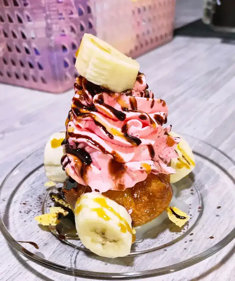 Banana with pink whipped cream and chocolate sauce