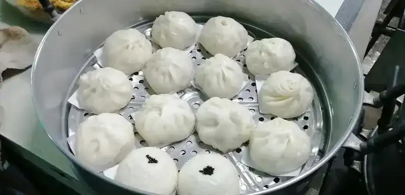 Steamed buns in a round aluminium steamer