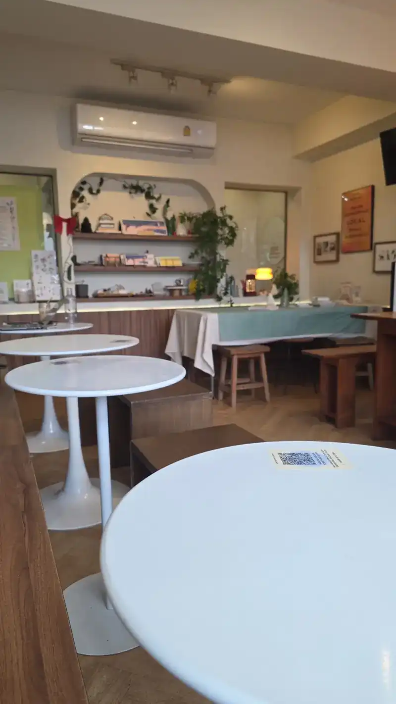 Round white tables in the shop, with shelves and the counter behind