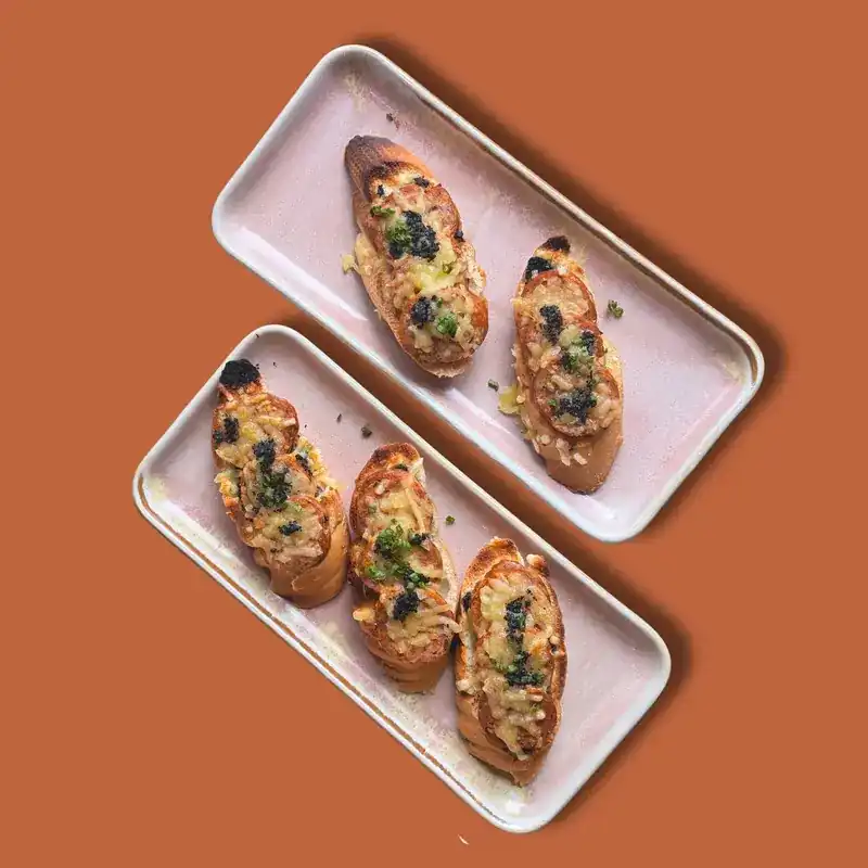 Chorizo and Manchego cheese toasts with black truffle on two long plates