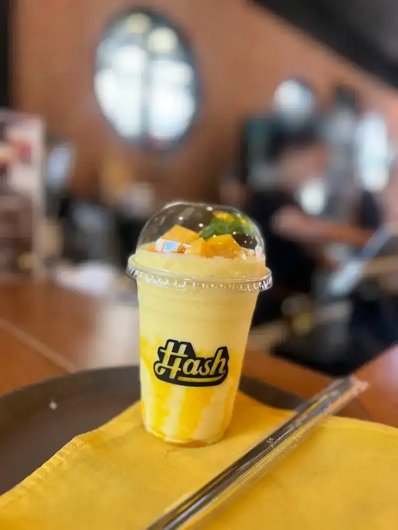 A mango smoothie in a Hash cup, topped with cubes of mango
