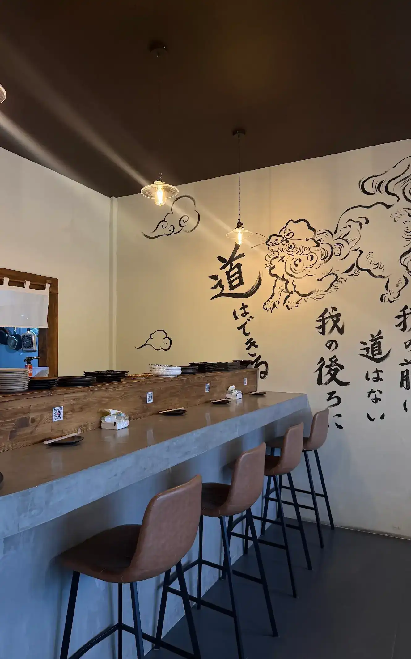 The counter at Daito: a concrete bar, leather stools and an ink-painted wall with a lion and Japanese lettering