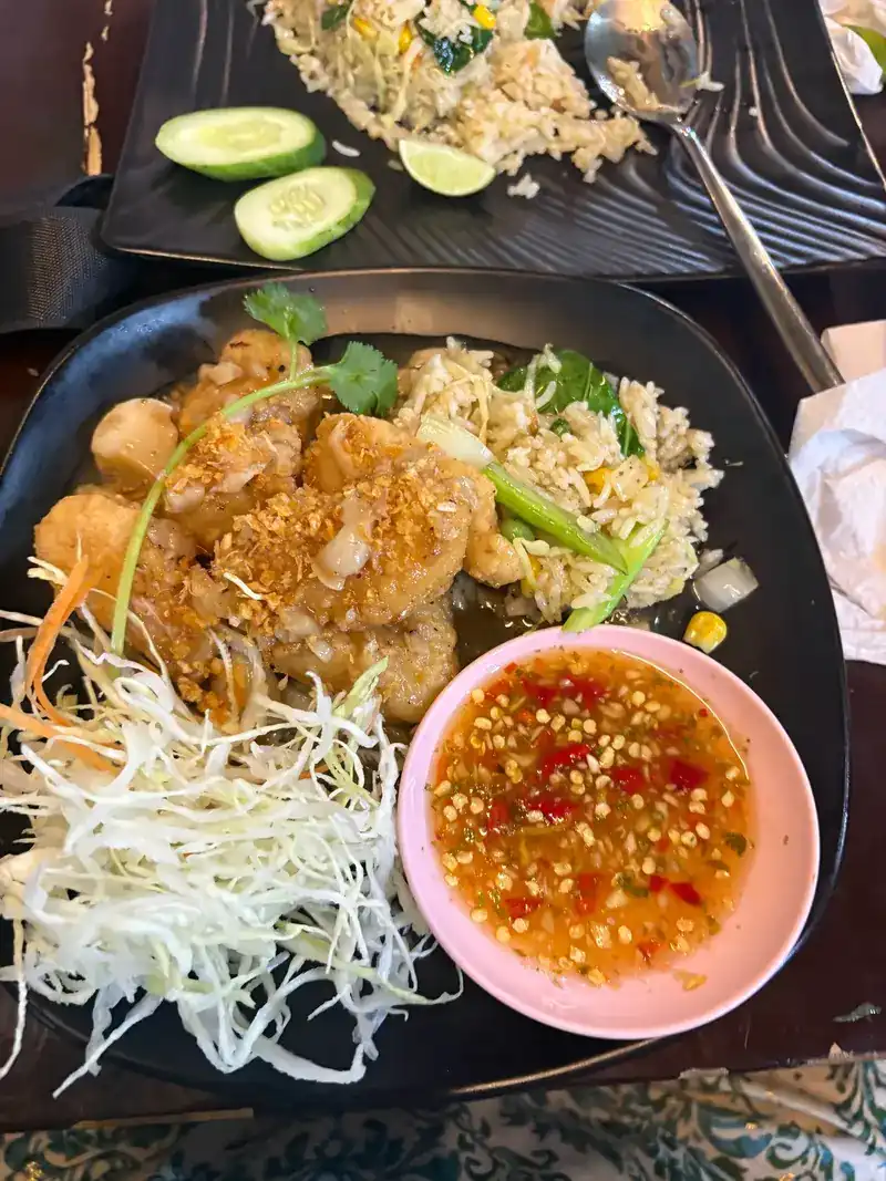 A fried dish topped with crispy garlic, with fried rice, shredded cabbage and a chilli dip