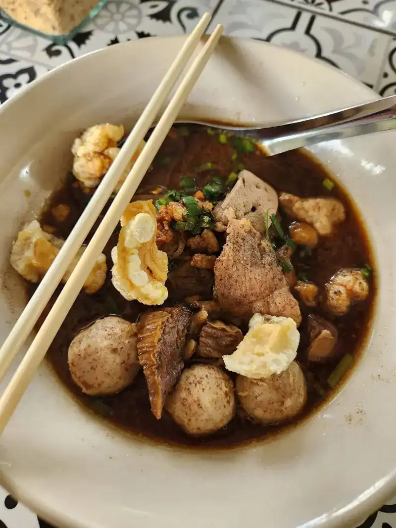 A bowl of boat noodles with meatballs, braised meat and crisp pork cracklings