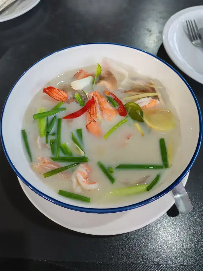 Tom yum with prawns in a blue-rimmed bowl
