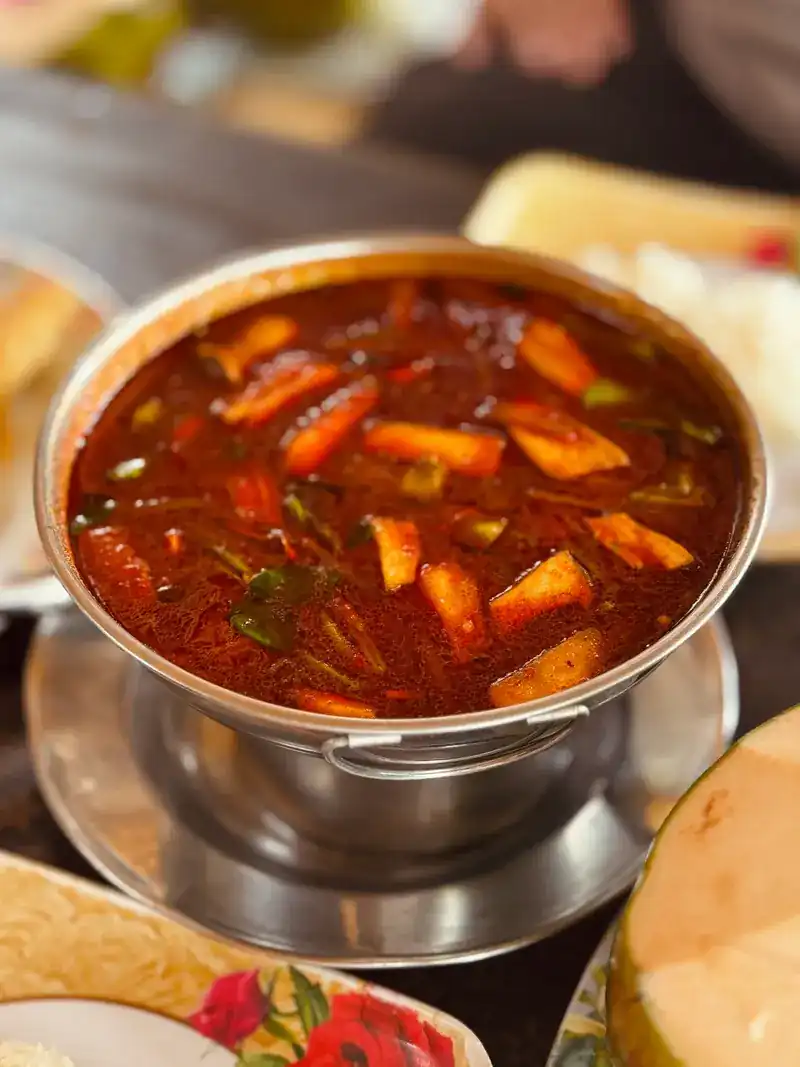 A hot pot of red, spicy soup on its burner