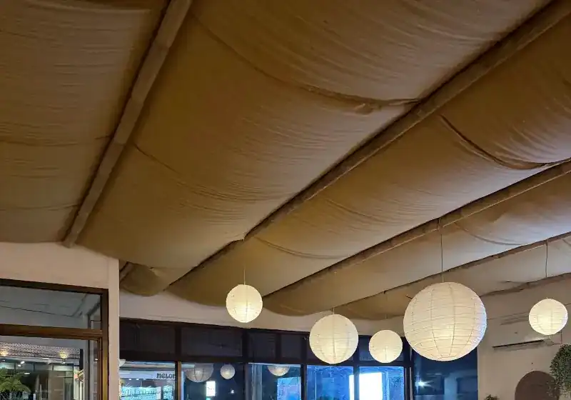 The dining room ceiling: draped cloth on bamboo poles and round white paper lanterns