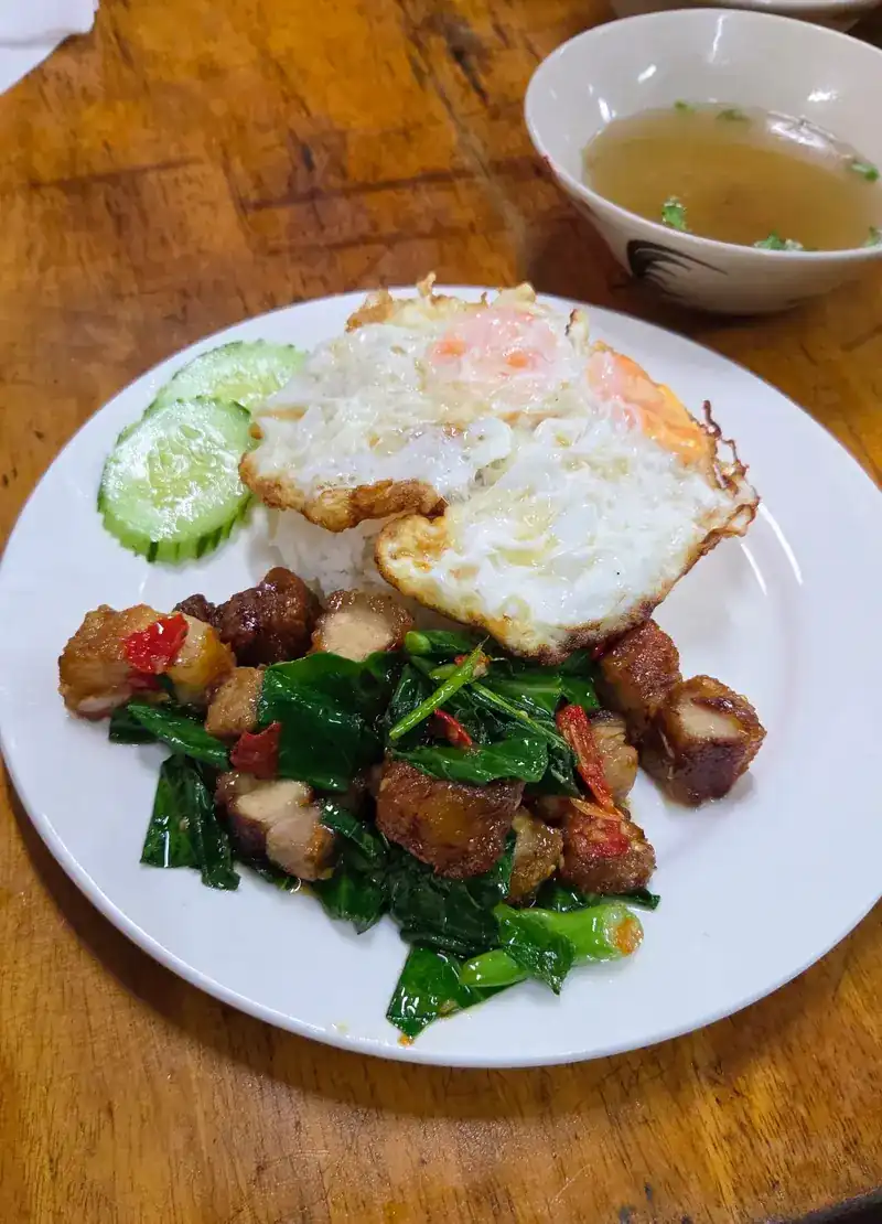 Kale with crispy pork and a fried egg over rice, with a cup of soup