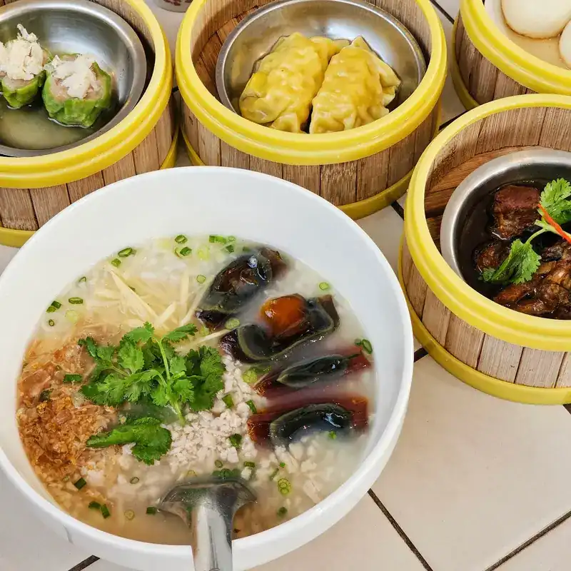 Rice congee with century egg and ginger, beside steamers of dim sum