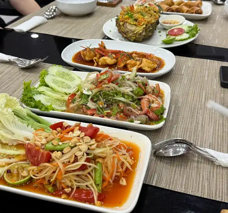 Papaya salad, a spicy prawn salad, a fried dish in sauce, pineapple fried rice and spring rolls shared on one table / ส้มตำ ยำกุ้ง ของทอดราดซอส ข้าวผัดสับปะรด และปอเปี๊ยะทอด วางรวมกันบนโต๊ะ