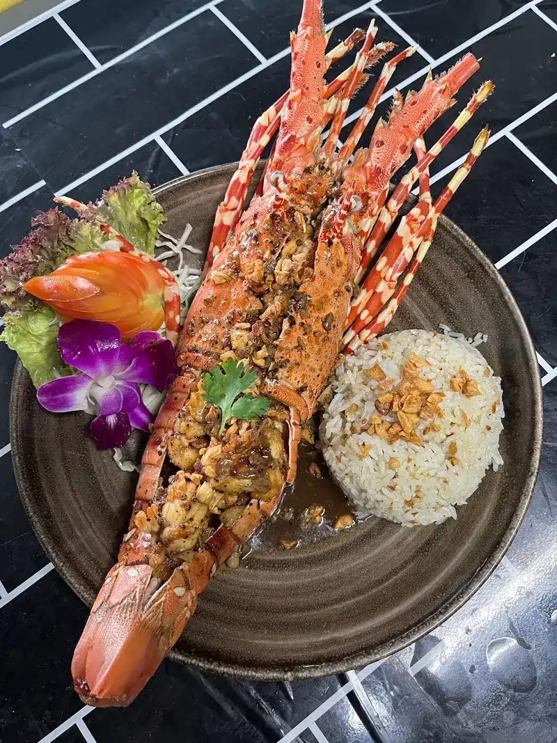 Lobster split and topped with fried garlic, served with rice and a purple orchid