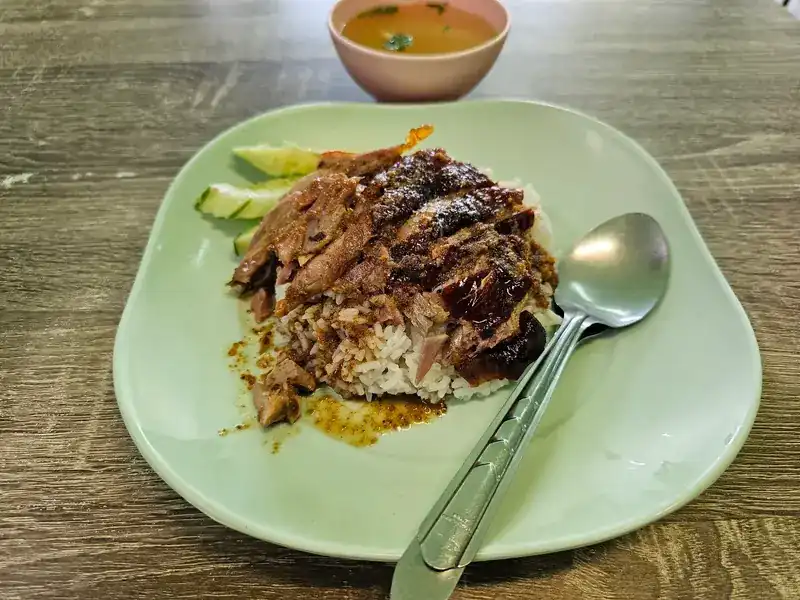 Duck rice on a pale green plate, with a bowl of soup